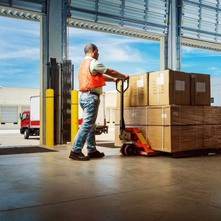 worker pushing an hydraulic hand pallet truck on a warehouse